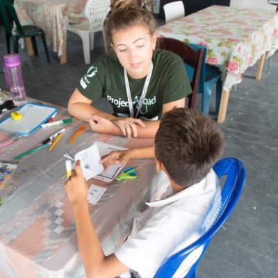 Maestra voluntaria ayuda a su estudiante con su pronunciación en inglés. Voluntaria ayuda a mejorar las habilidades de alfabetización de sus estudiantes en su voluntariado de educación en Belice.